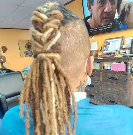 Person with dreadlocks in a salon. Braided top with long hanging locks. Wearing a mask.