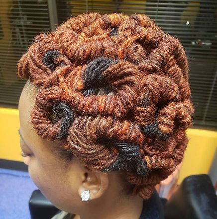 Woman with intricately styled, reddish-brown locs and some black strands.