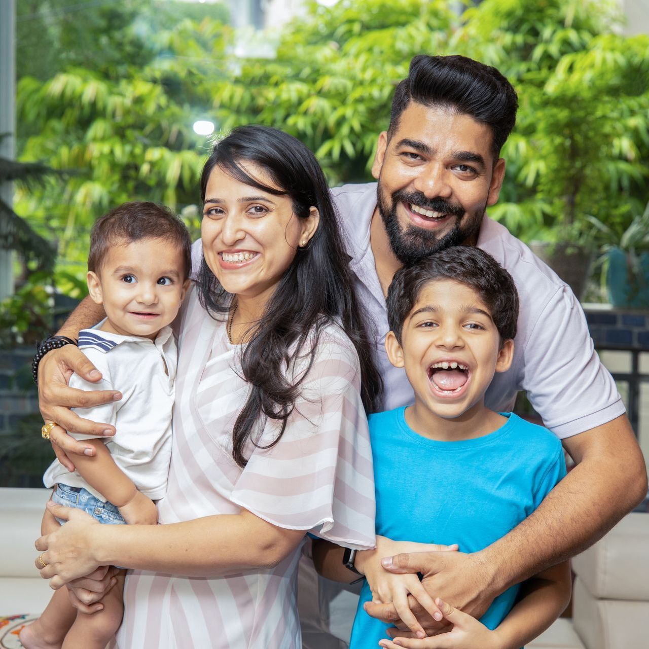 A family including mom, dad and two children are smiling and laughing