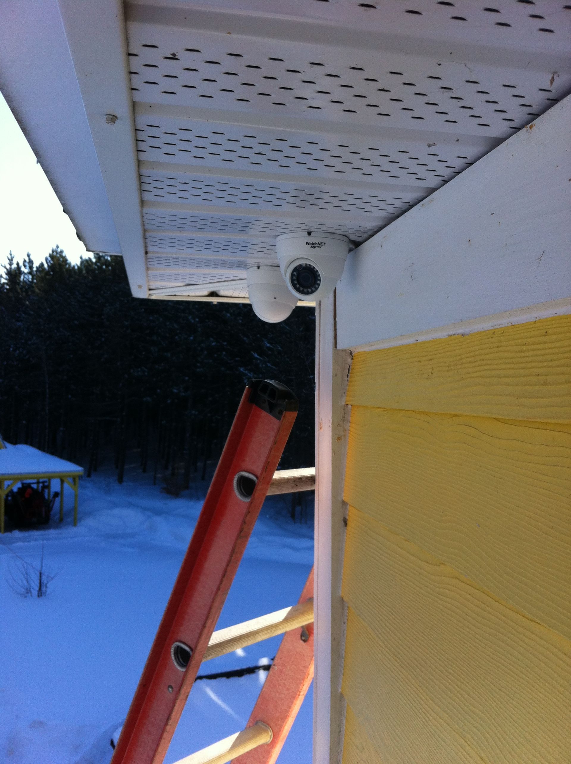 Une échelle rouge est attachée au côté d'une maison