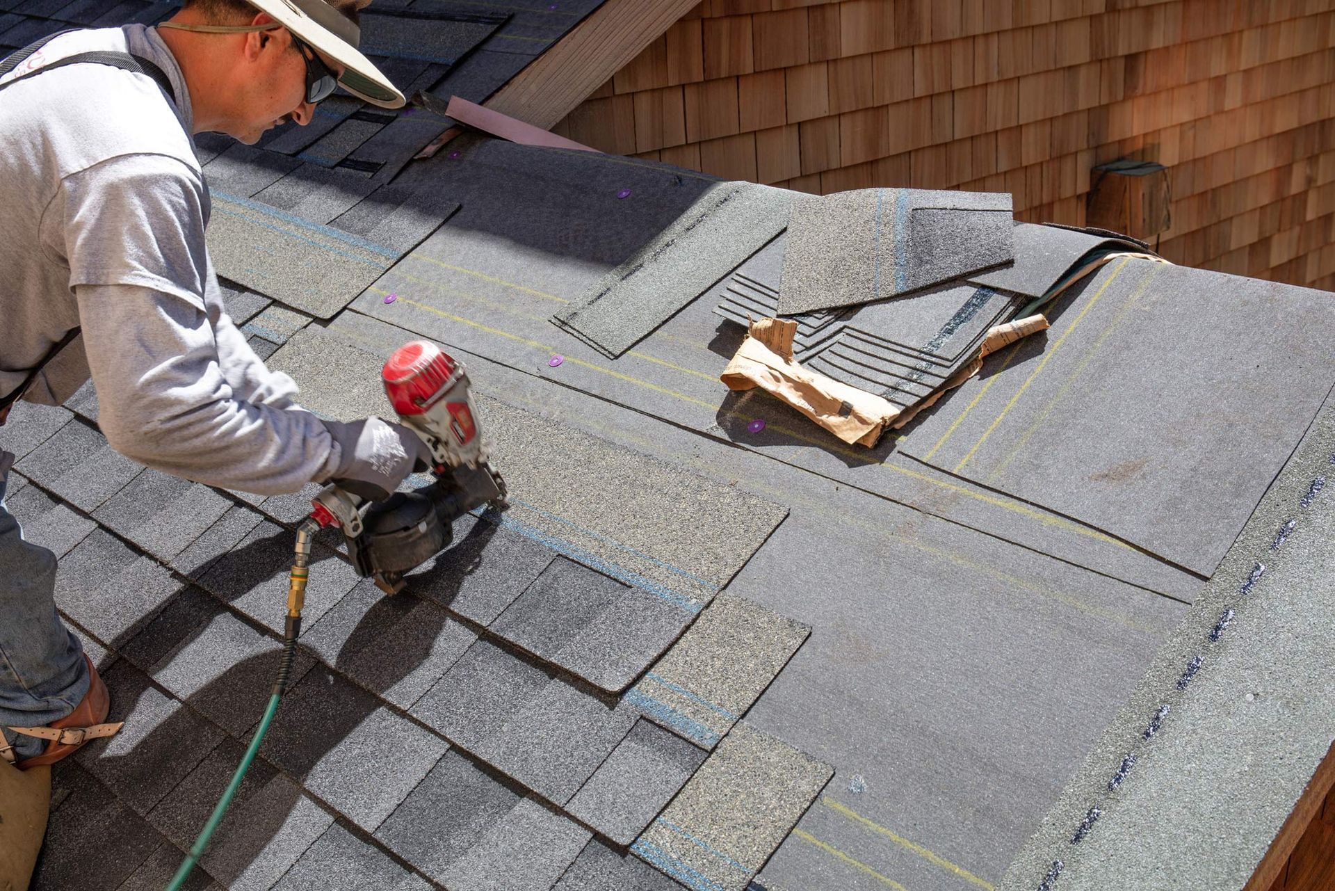 A roof contractor is installing a new roof with a red nail gun