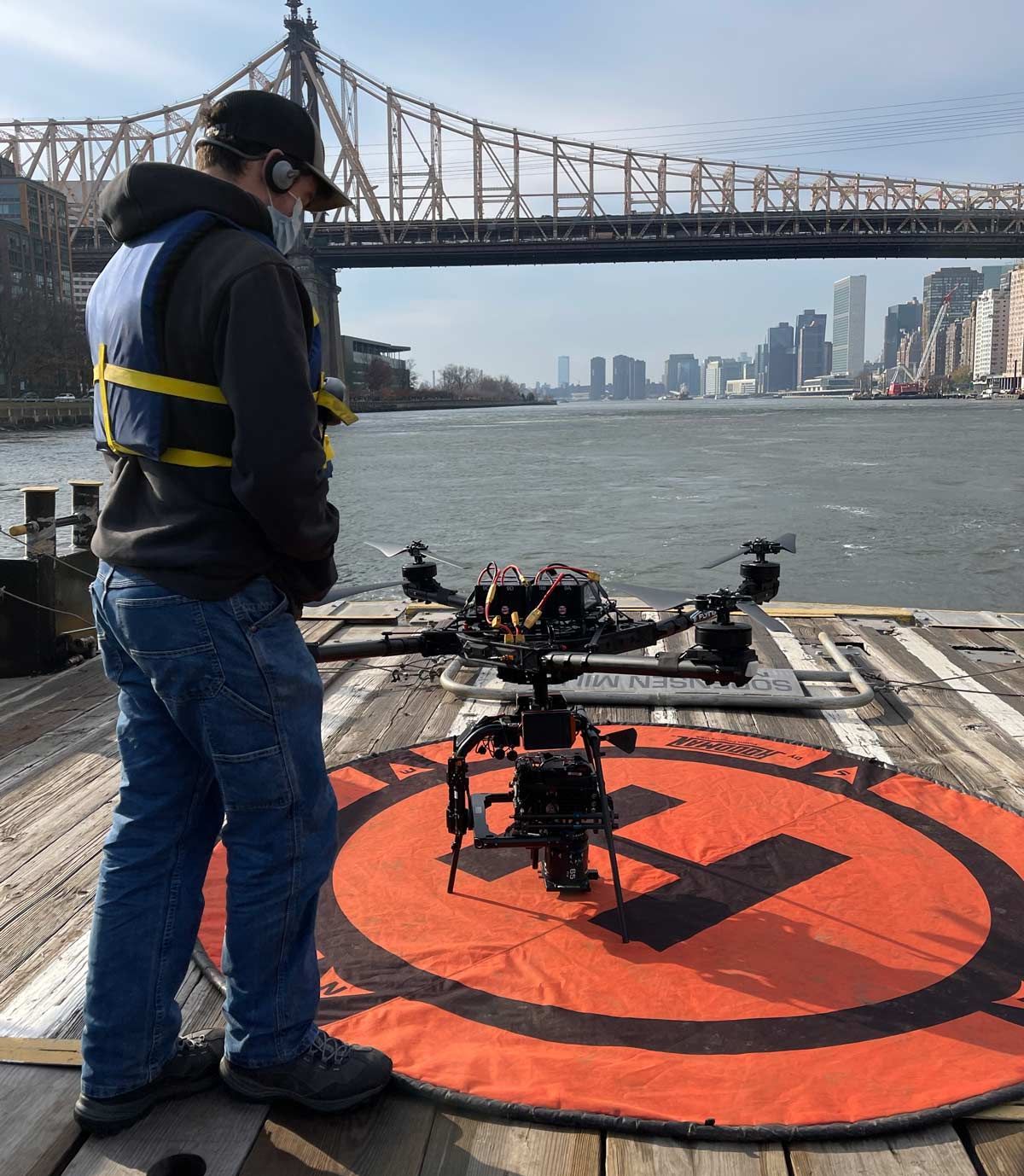 A man stands on a dock looking at a drone