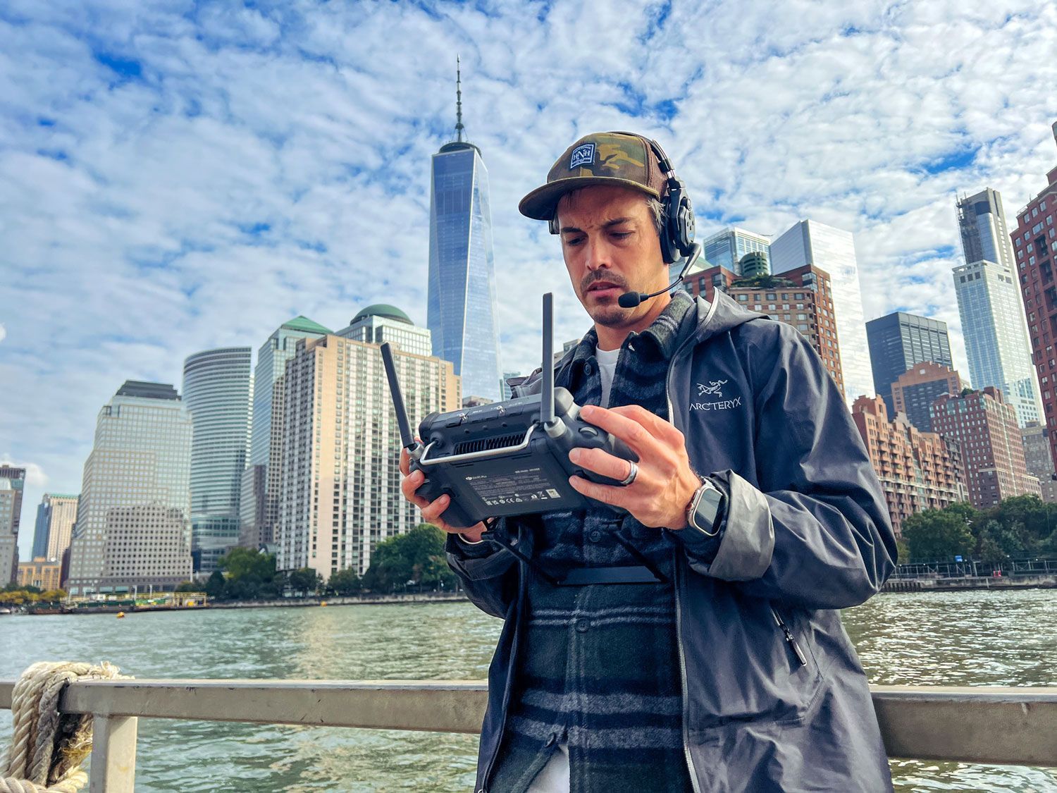 A man is holding a remote control in front of a city skyline.