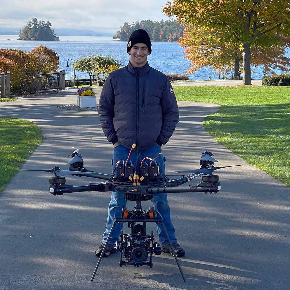 a man in a black jacket is standing next to a drone