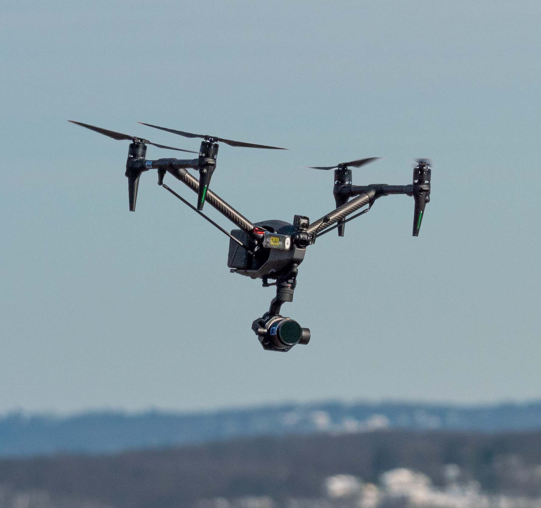 A drone with a camera attached to it is flying in the sky