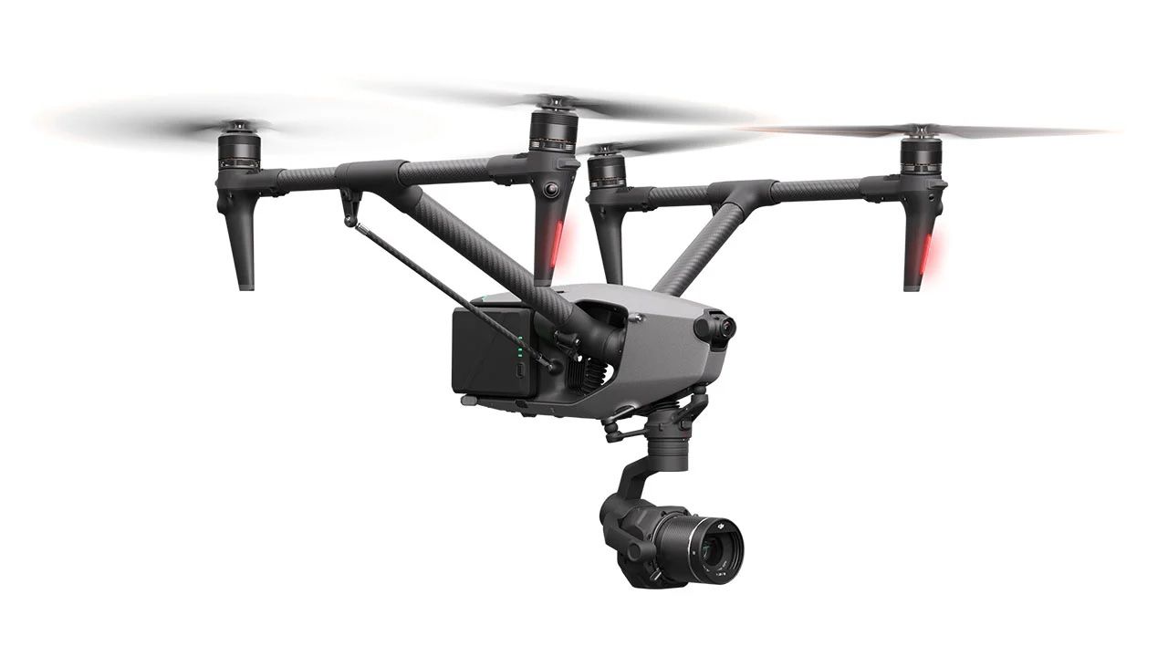 A drone with a camera attached to it is flying in the air on a white background.