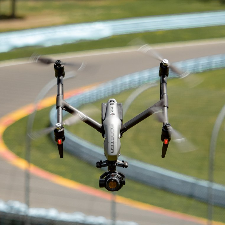 A drone with a camera attached to it is flying over a race track