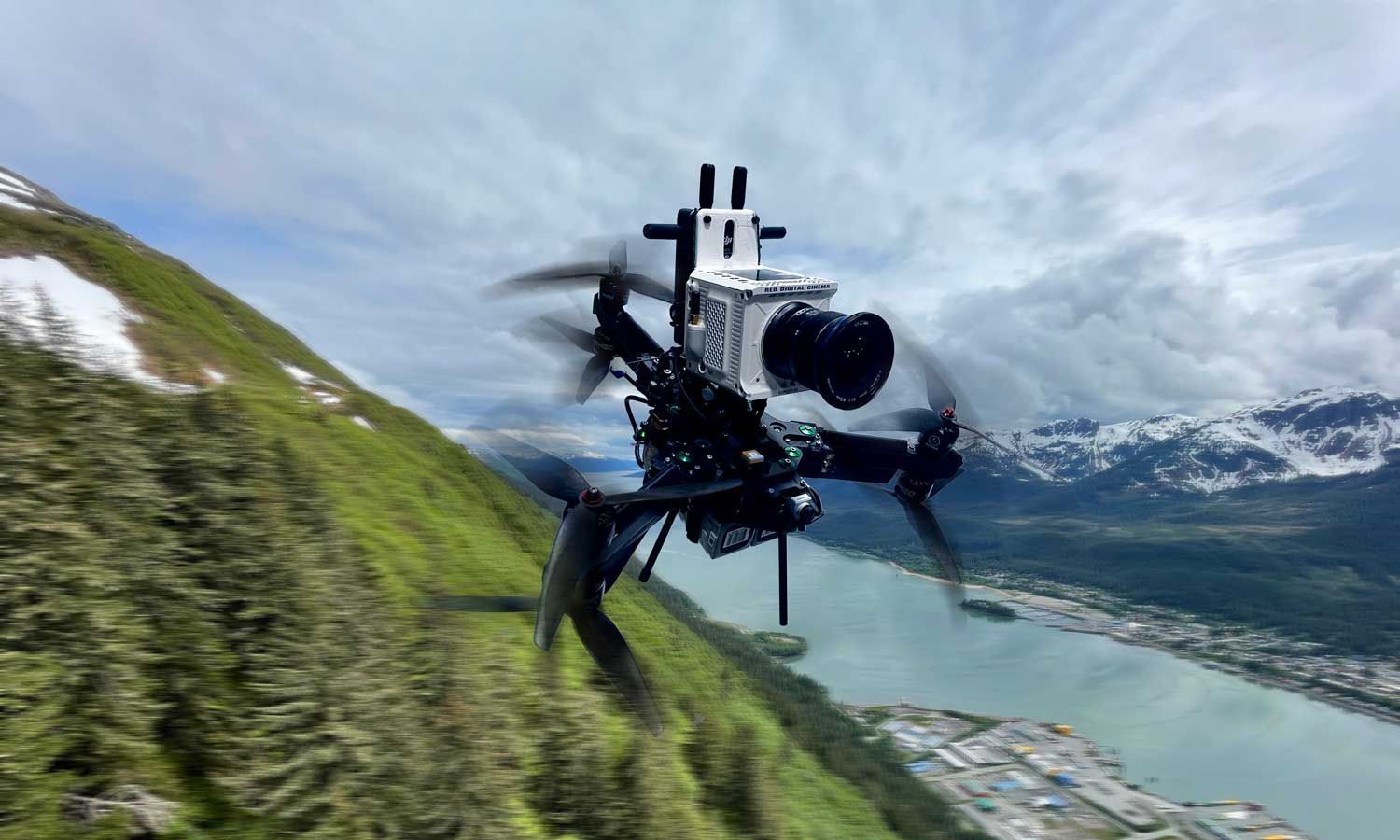 A drone is flying over a mountain with a camera attached to it.