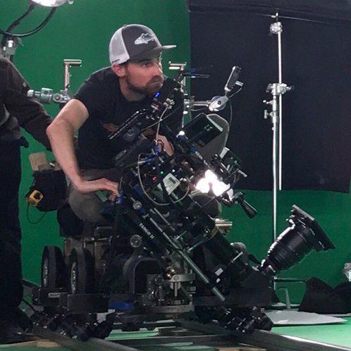 A man in a hat is sitting in front of a camera