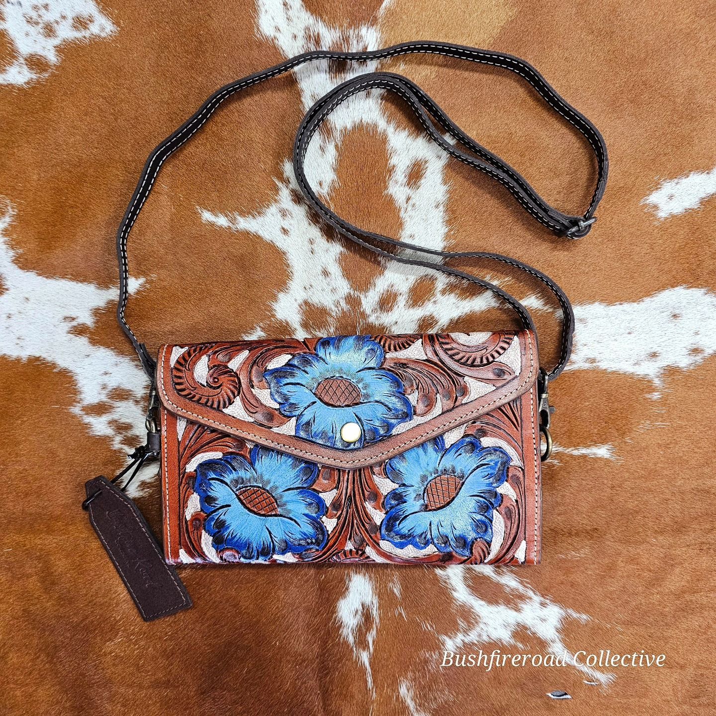 Brown Leather Crossbody Bag With Blue Floral Design, On A Brown And White Cowhide Background — Bushfire Road Collective in Mareeba ,QLD