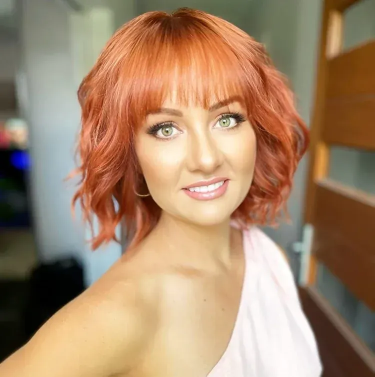 Woman With Red Hair And Bangs, Smiling, Wearing A Pink Off-shoulder Top — Bushfire Road Collective in Mareeba ,QLD
