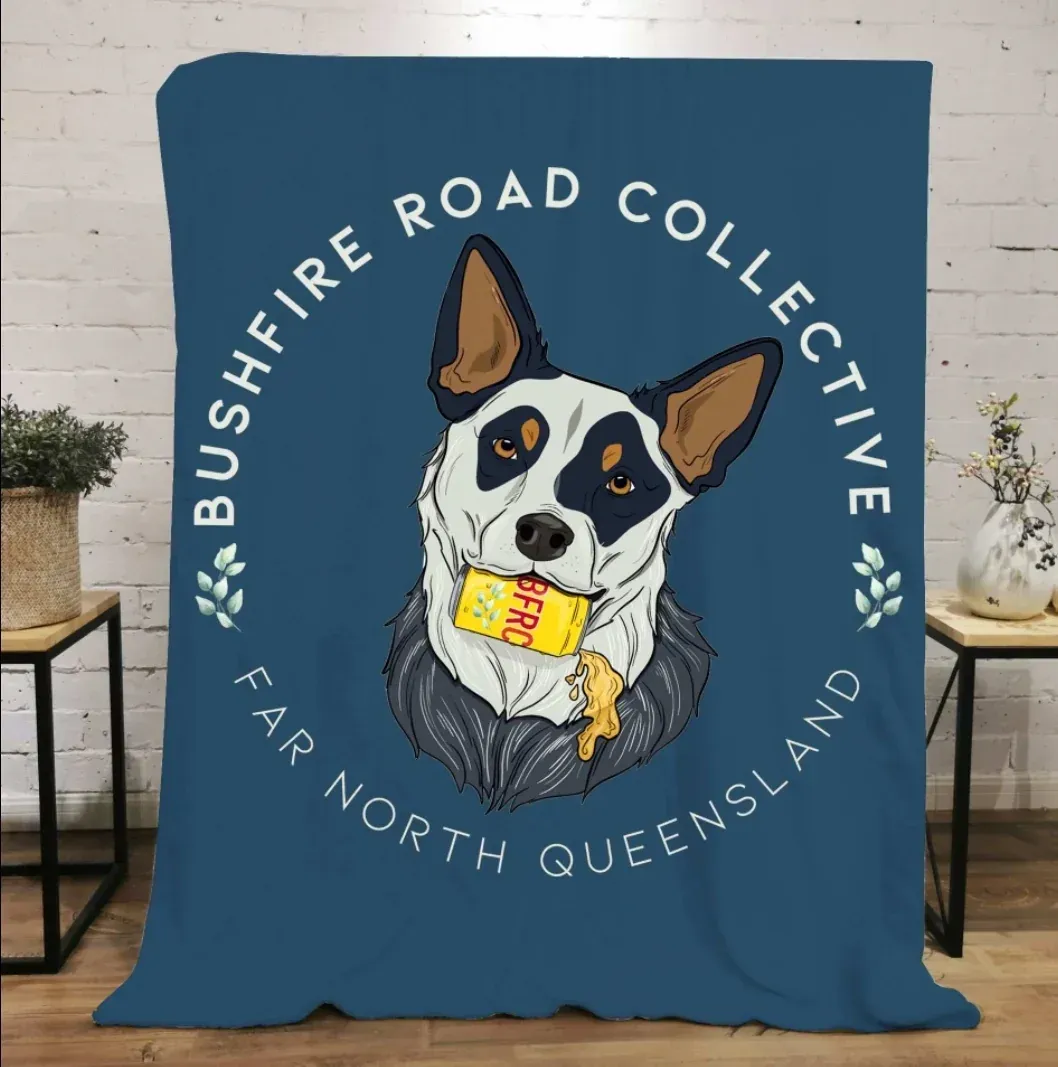 Blue Throw With Dog Logo, Text "Bushfire Road Collective, Far North Queensland." Dog Holds Yellow Item — Bushfire Road Collective in Mareeba ,QLD