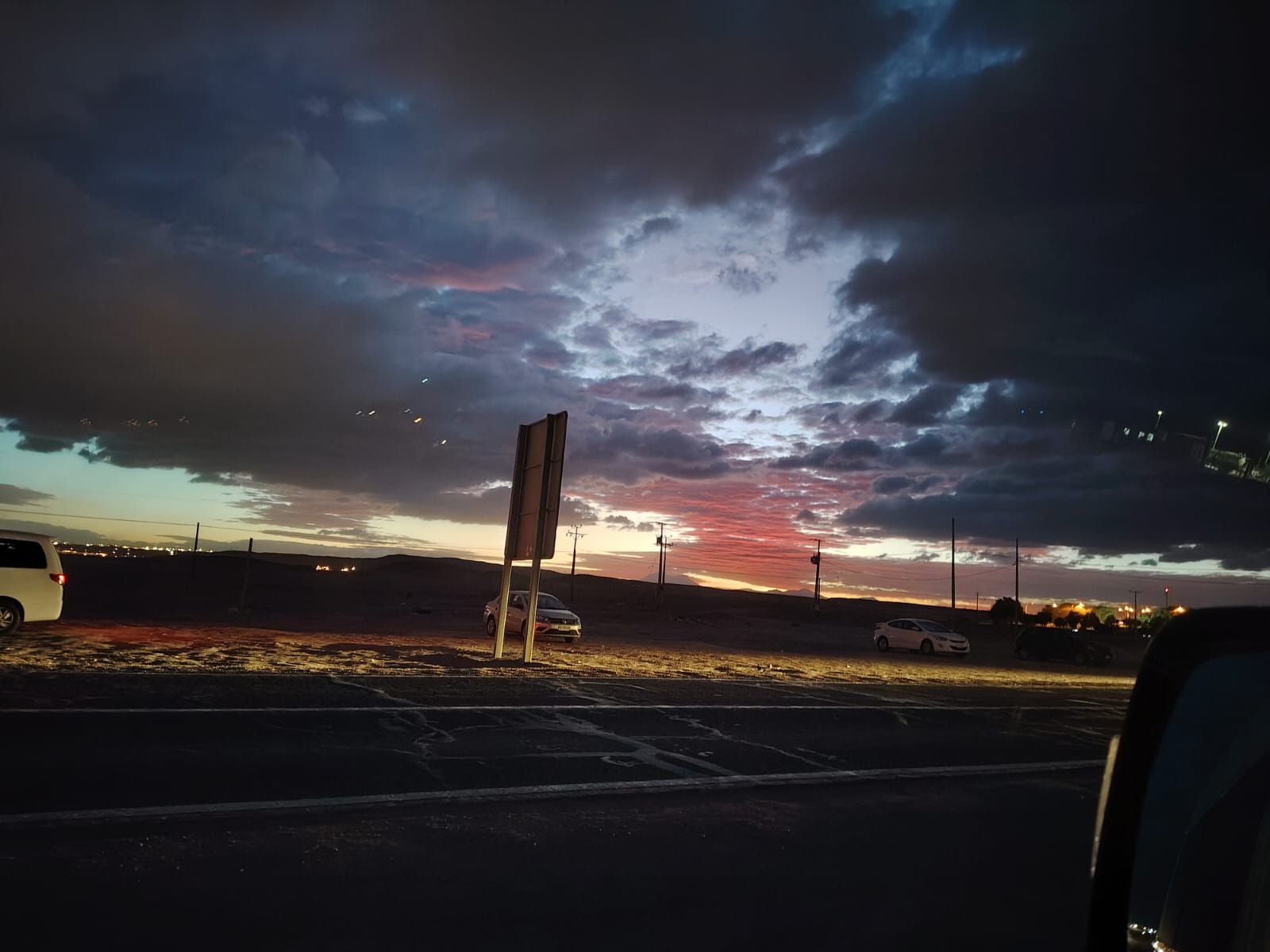 Una puesta de sol con luz rosada y naranja que brilla a través de las nubes oscuras