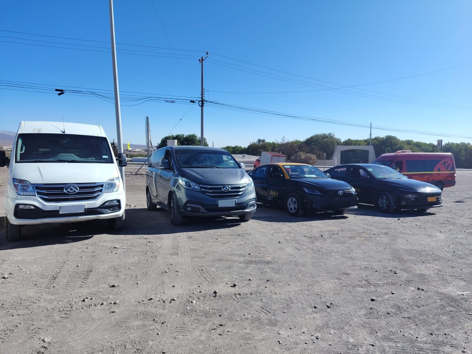 Una furgoneta blanca, una minivan gris y dos sedanes oscuros estaban estacionados en fila