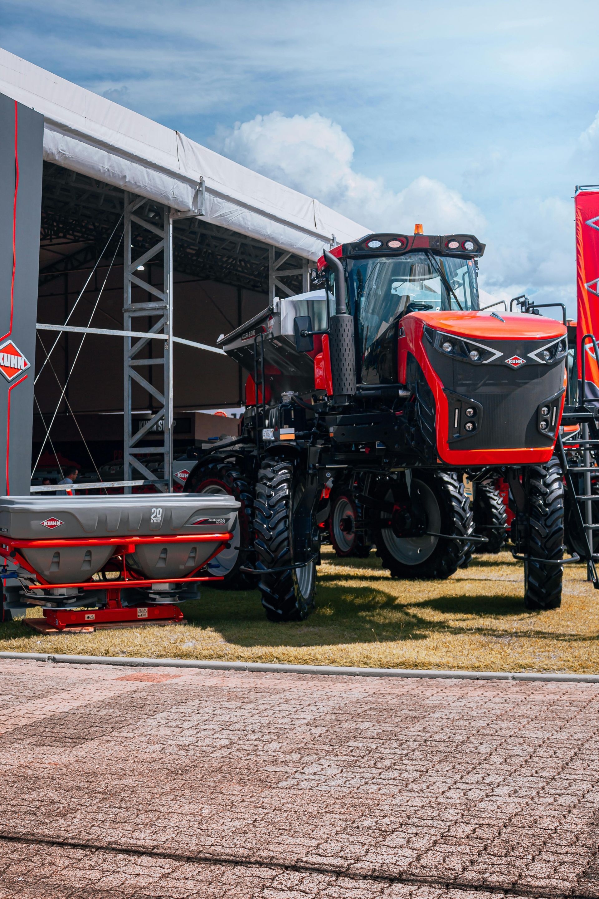 Red tractor parked beside a tent at an outdoor farm equipment display