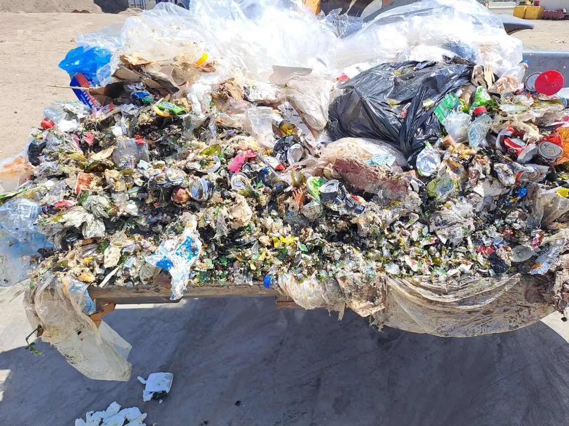 Heap of mixed trash including plastic, styrofoam, and bags in a bin.