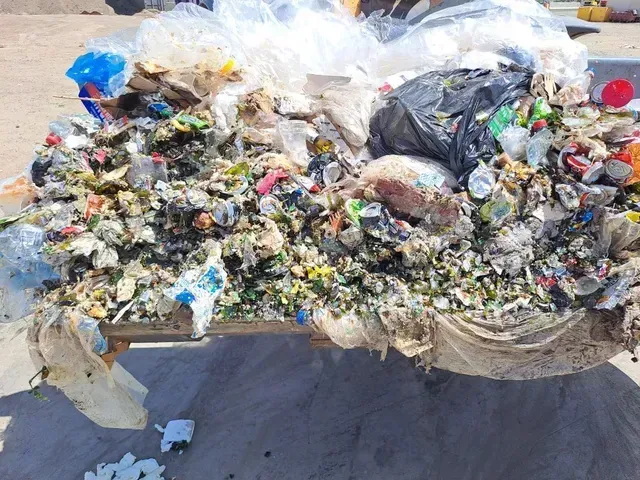 Heap of mixed trash including plastic, styrofoam, and bags in a bin.