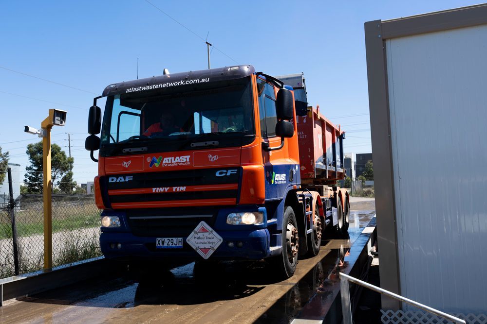 Orange dump truck on a scale, blue cab details, sunny outdoor setting.