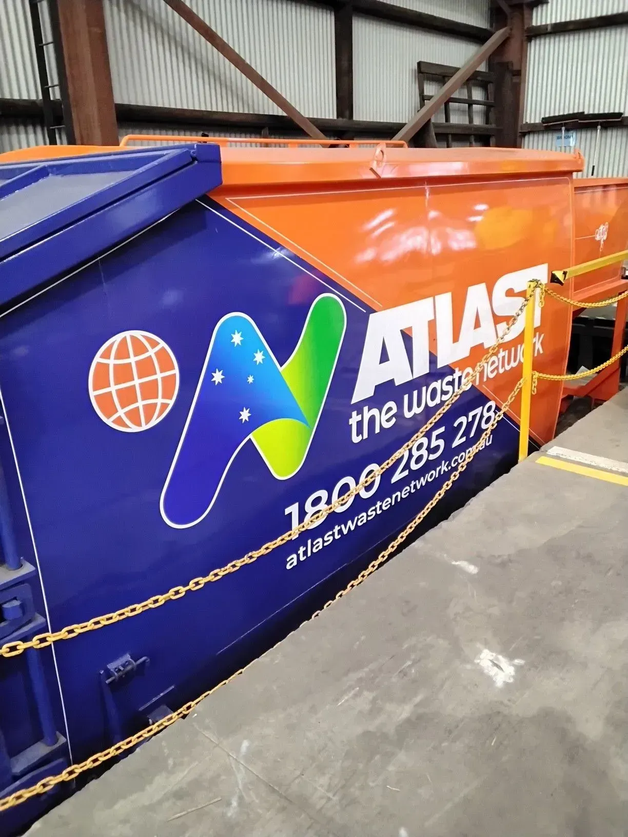 Blue and orange Atlas waste collection truck with logo and contact information.