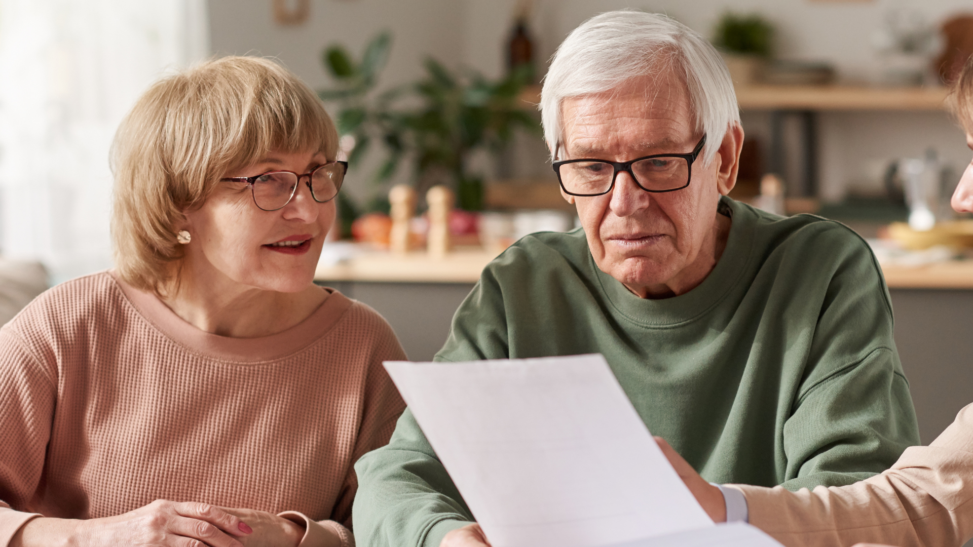 Senior couple reviewing documents with a professional in a home setting.