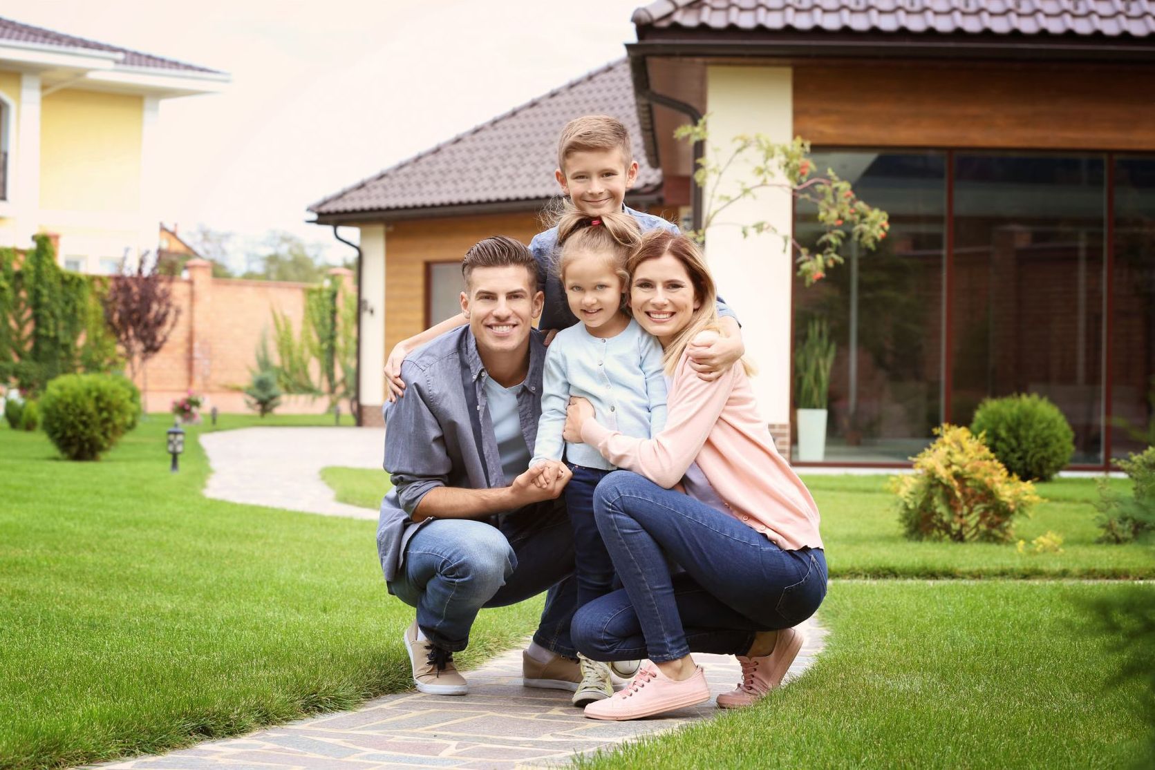 smiling family of four in front of property