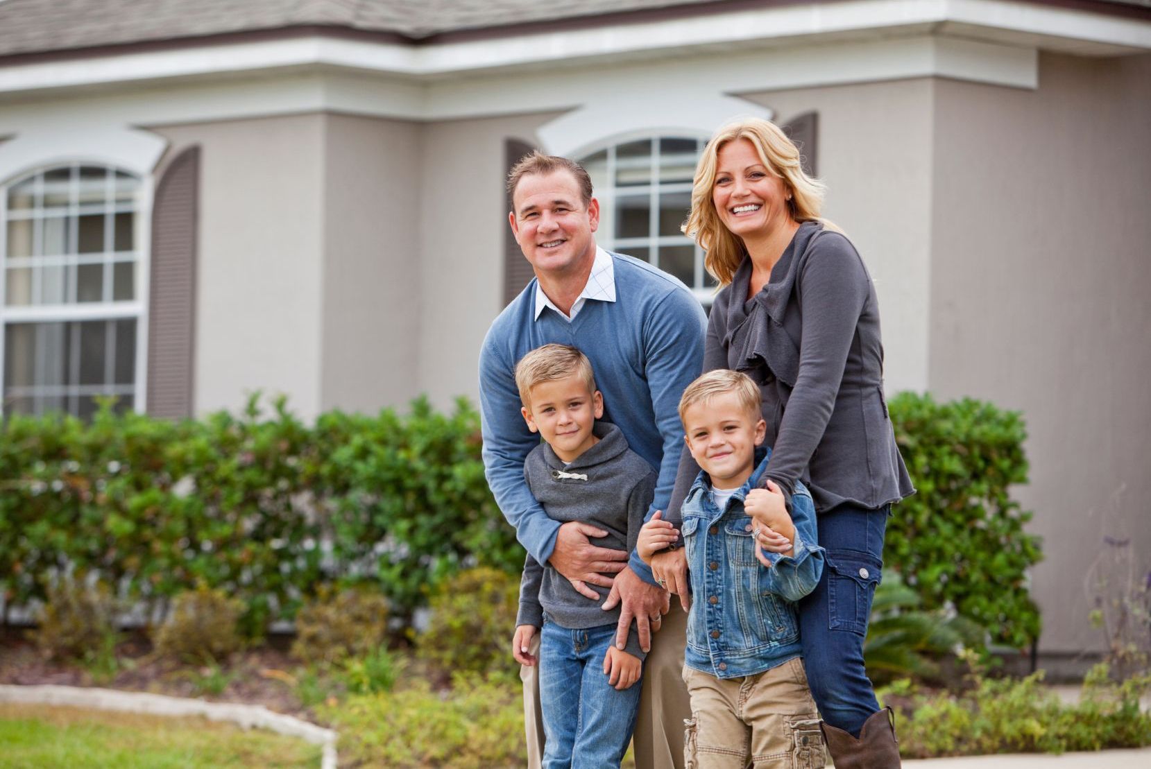 family of four standing in front of real estate property