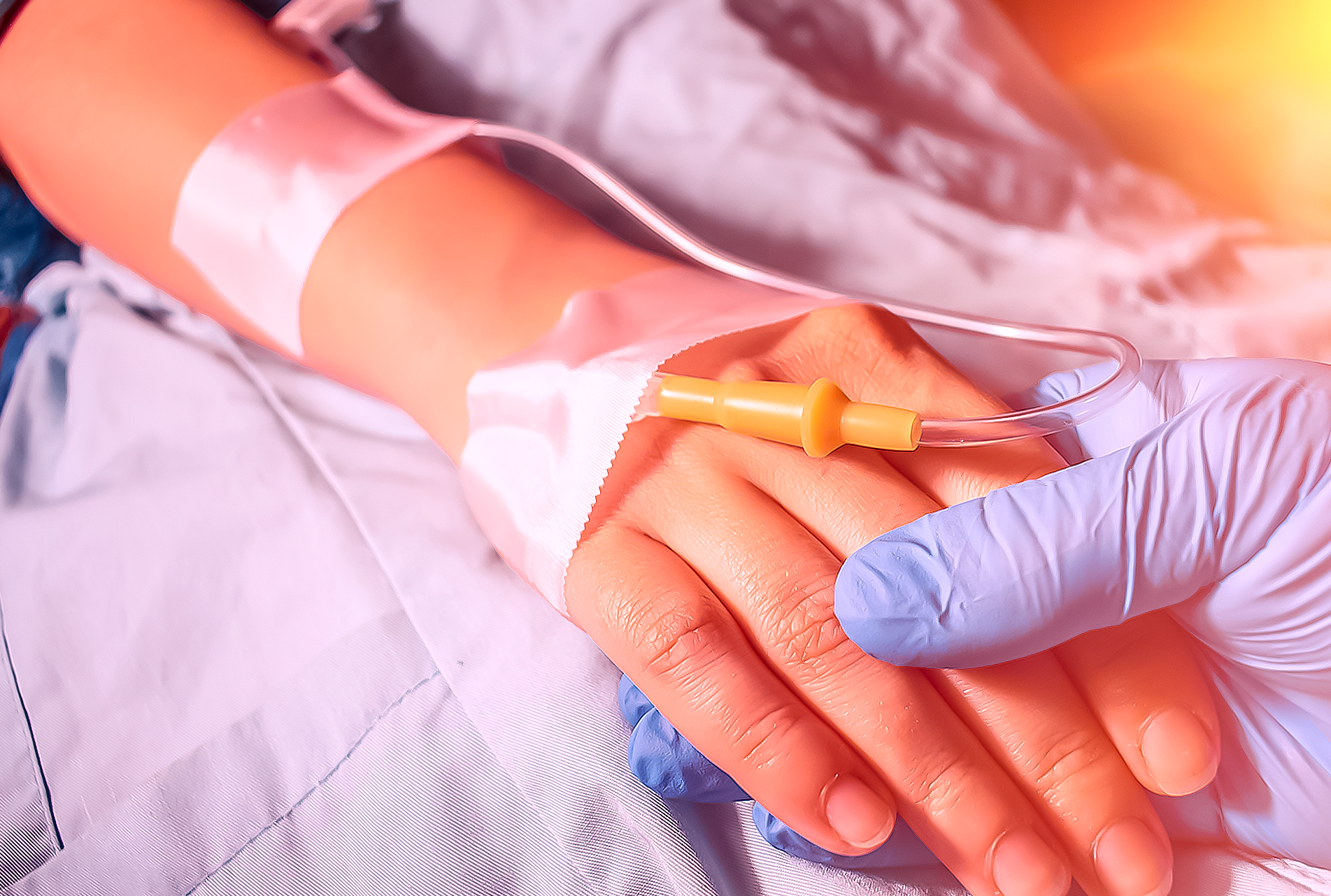 Uma pessoa com uma intravenosa no braço está segurando a mão de outra pessoa.