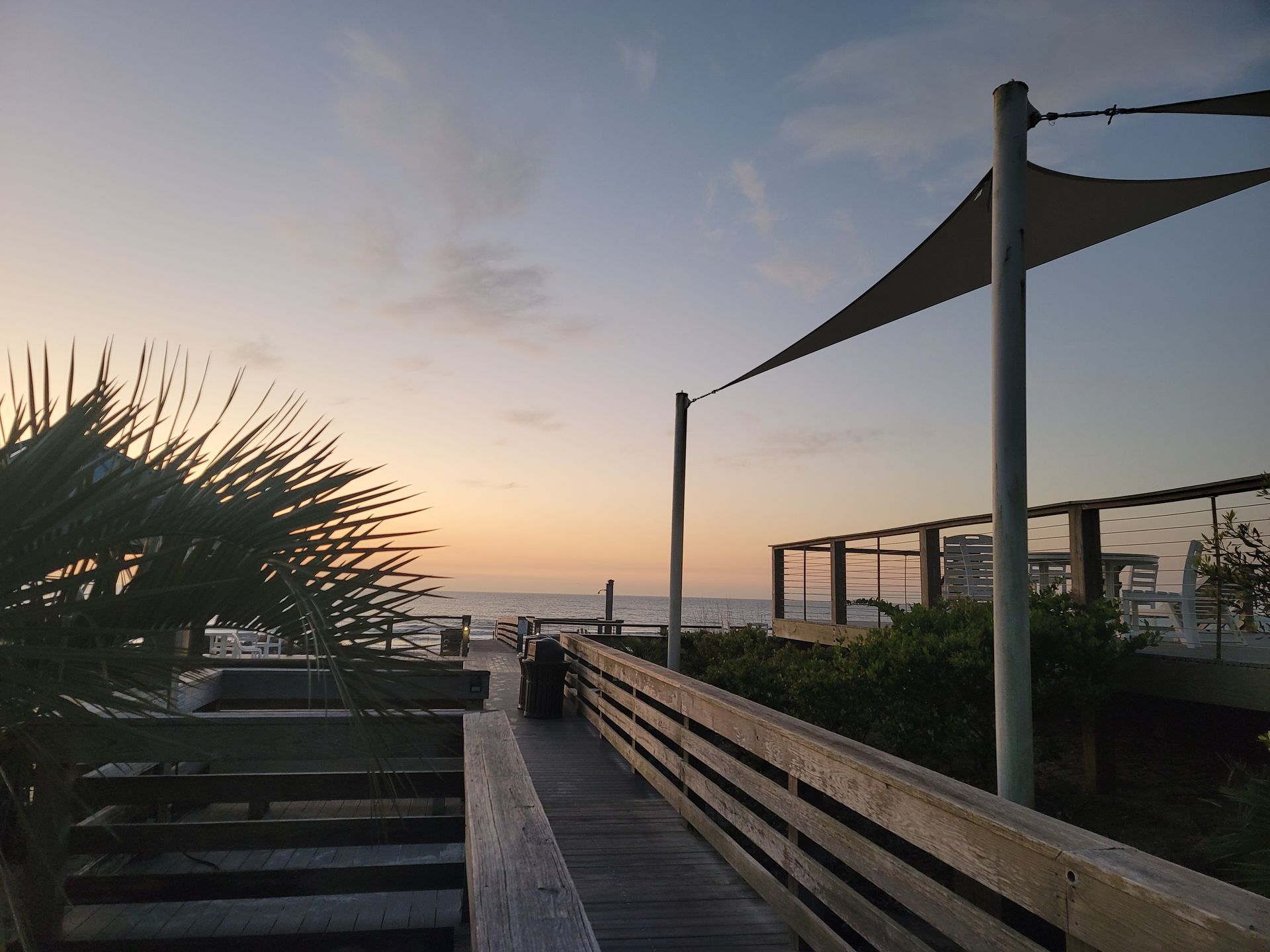 A wooden walkway leading to the ocean at sunset