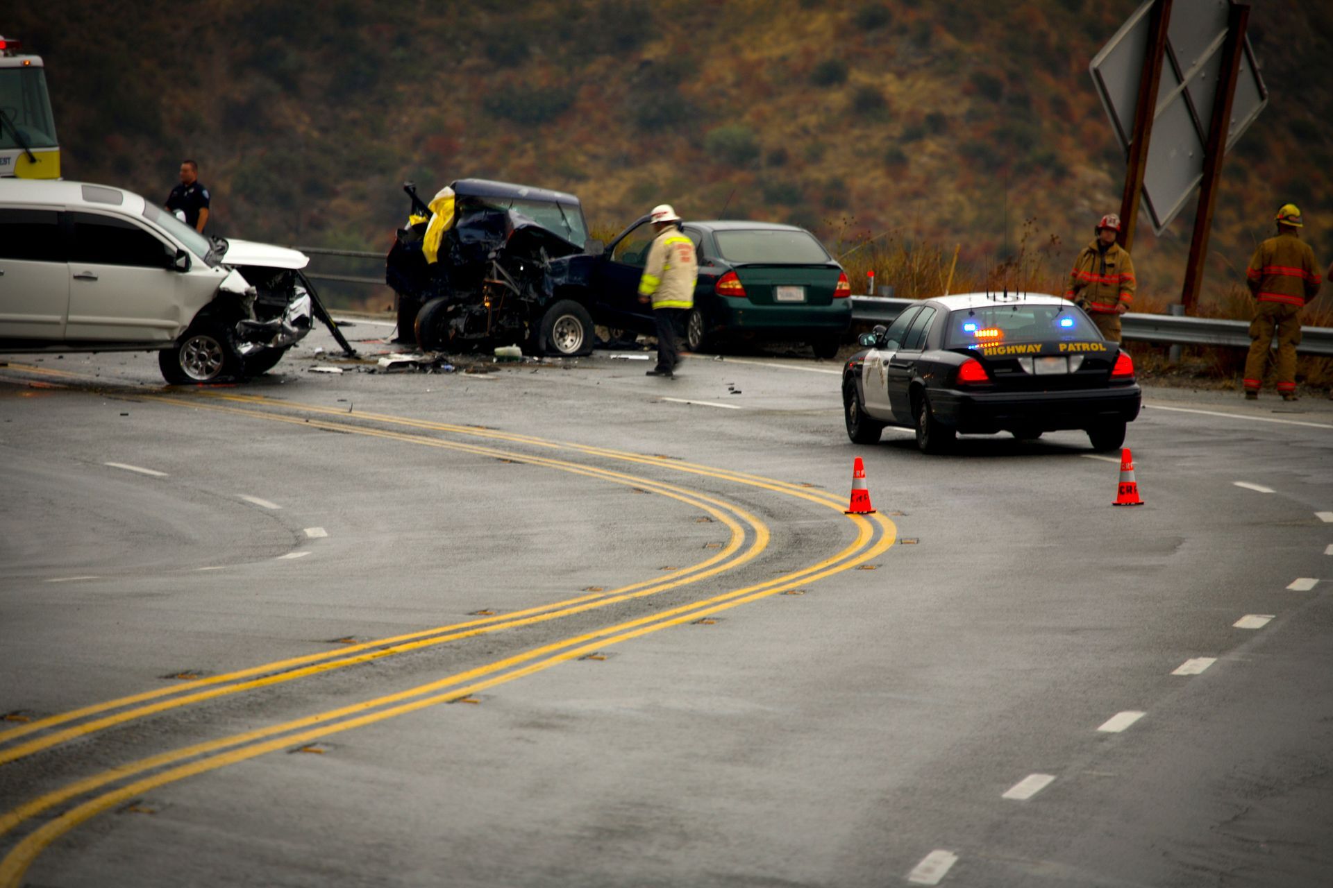 A police car is driving past a car accident on a highway.
