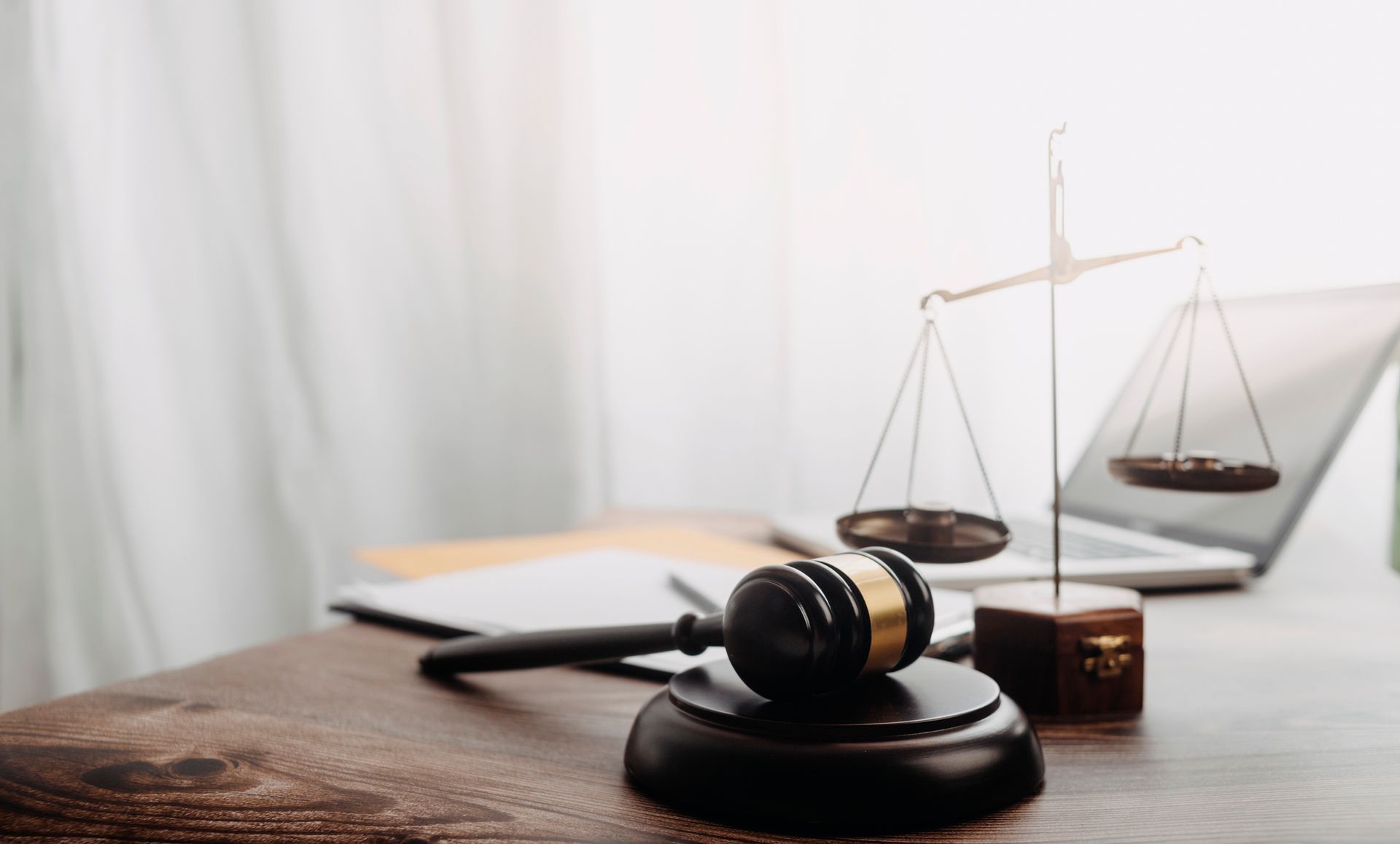 A judge 's gavel and scales of justice are on a wooden table.