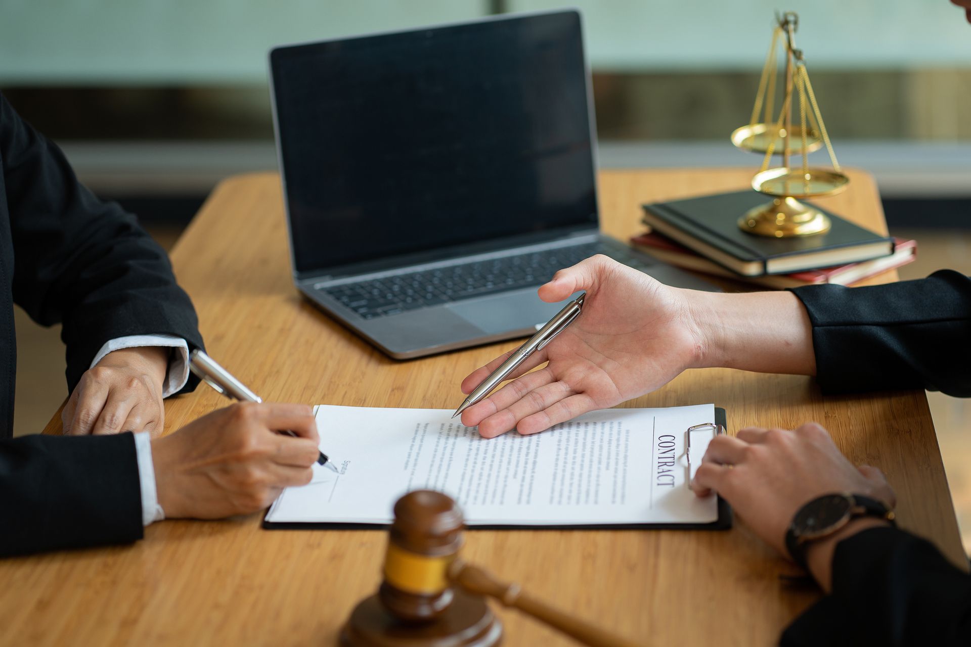 Two people are sitting at a table with a laptop and a judge 's gavel. Two people are sitting at a table with a laptop and a judge 's gavel.