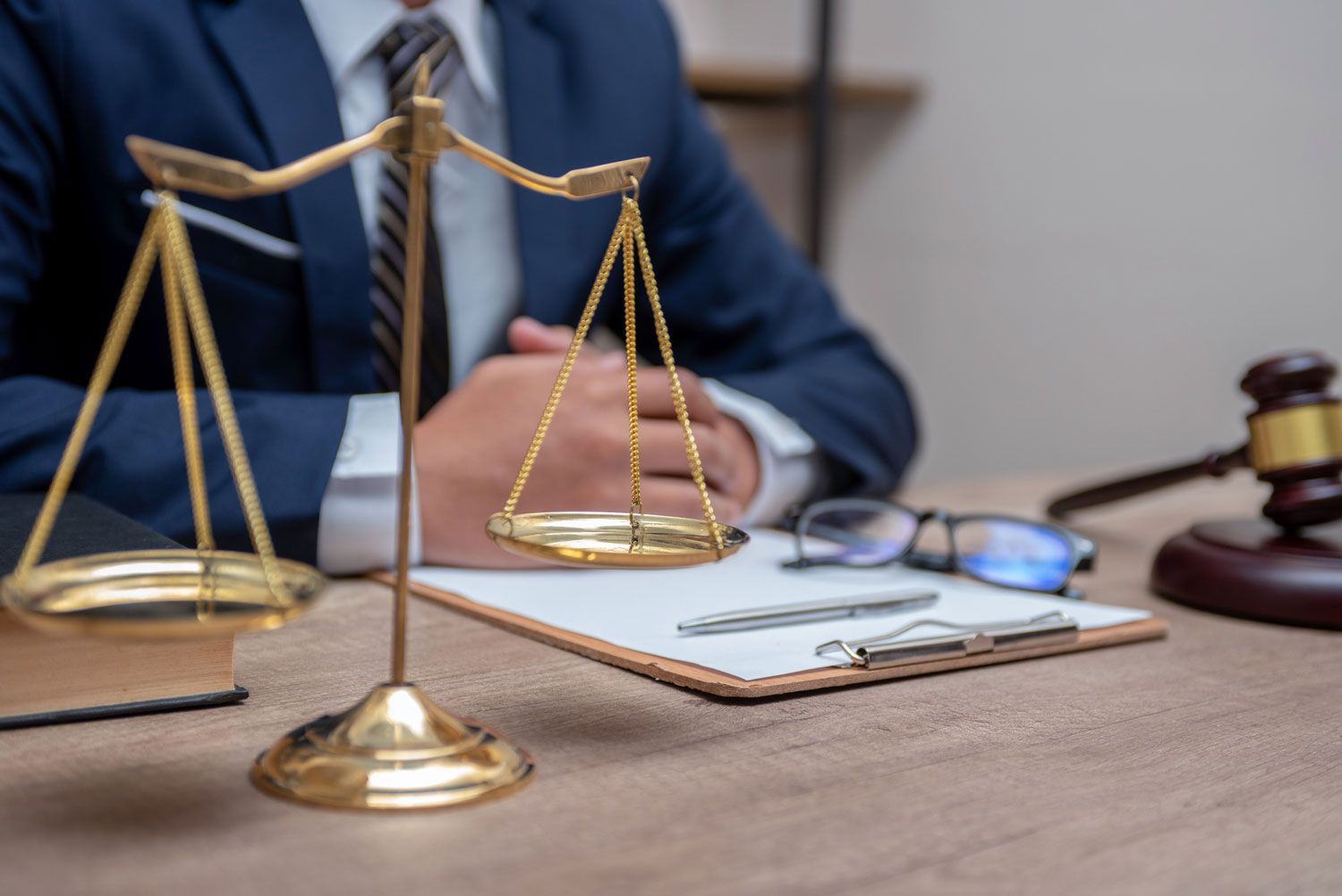 A lawyer is sitting at a desk with scales of justice and a gavel.