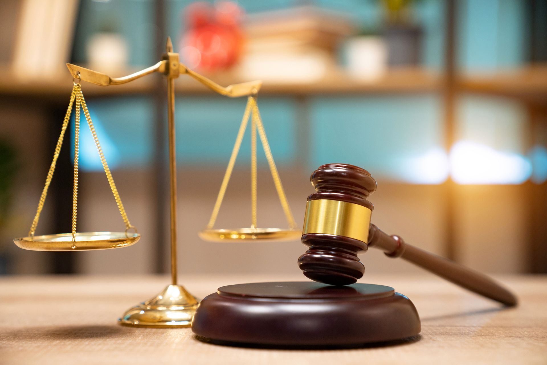 A wooden judge 's gavel and scales of justice on a wooden table.