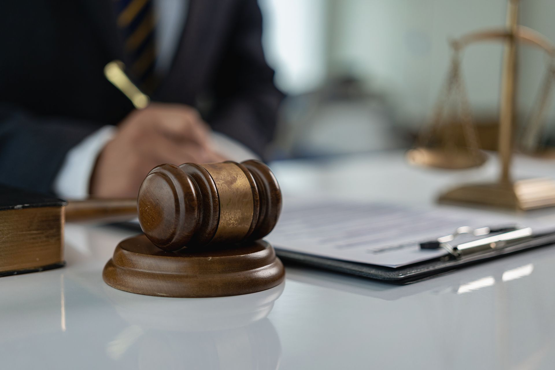 A judge 's gavel is sitting on a table next to a clipboard and scales of justice.