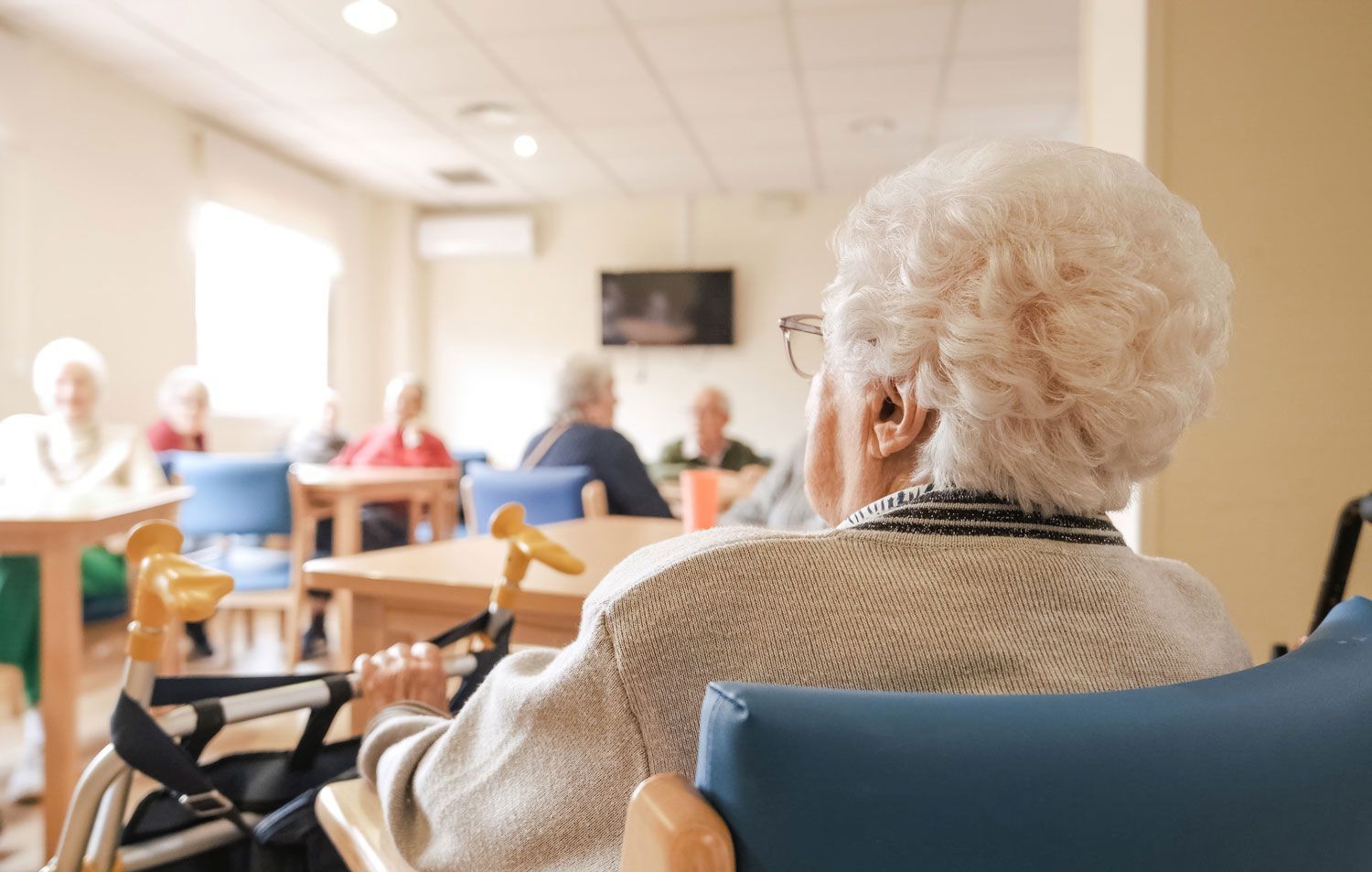 An elderly woman is sitting in a wheelchair in a nursing home. An elderly woman is sitting in a wheelchair in a nursing home.