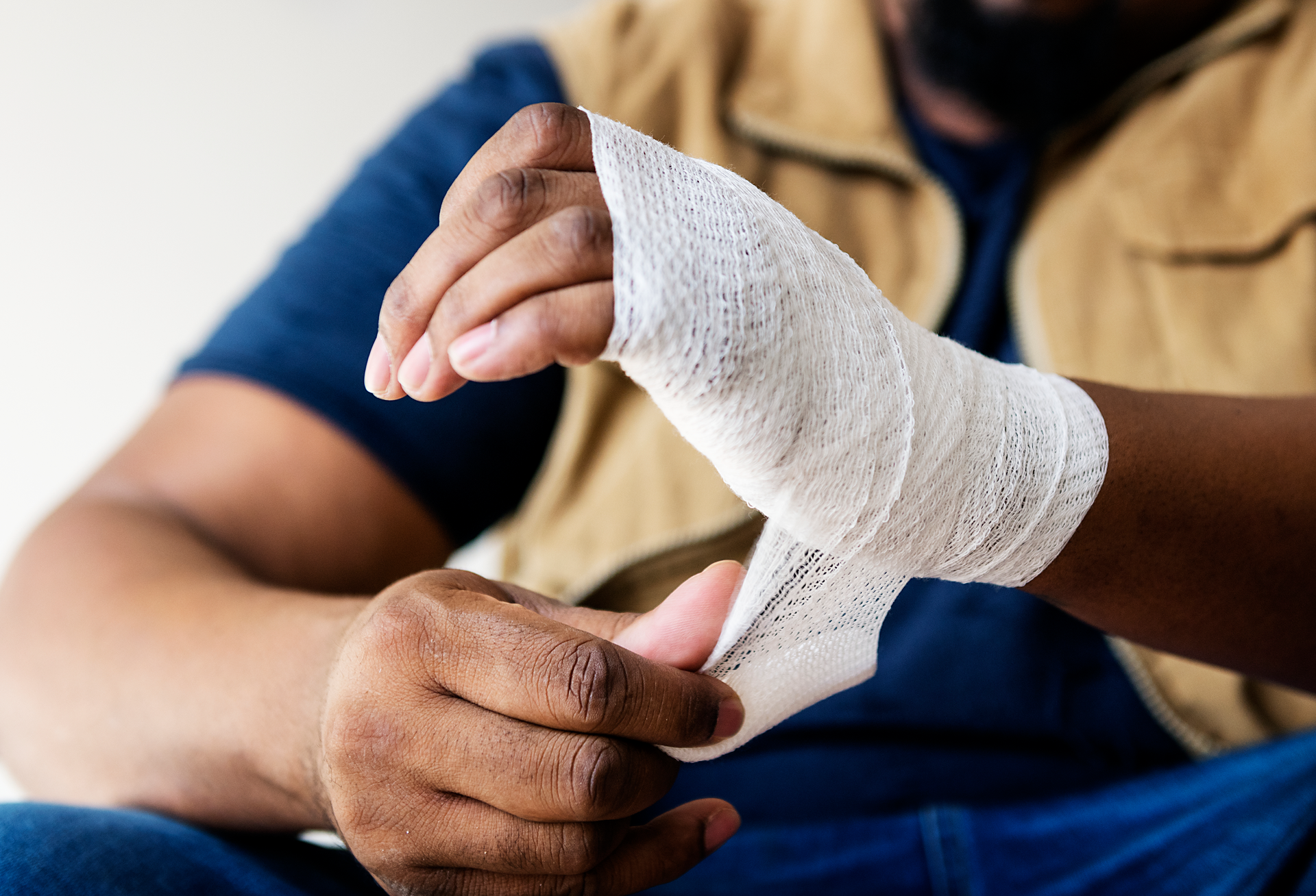 A man is wrapping his wrist with a bandage.