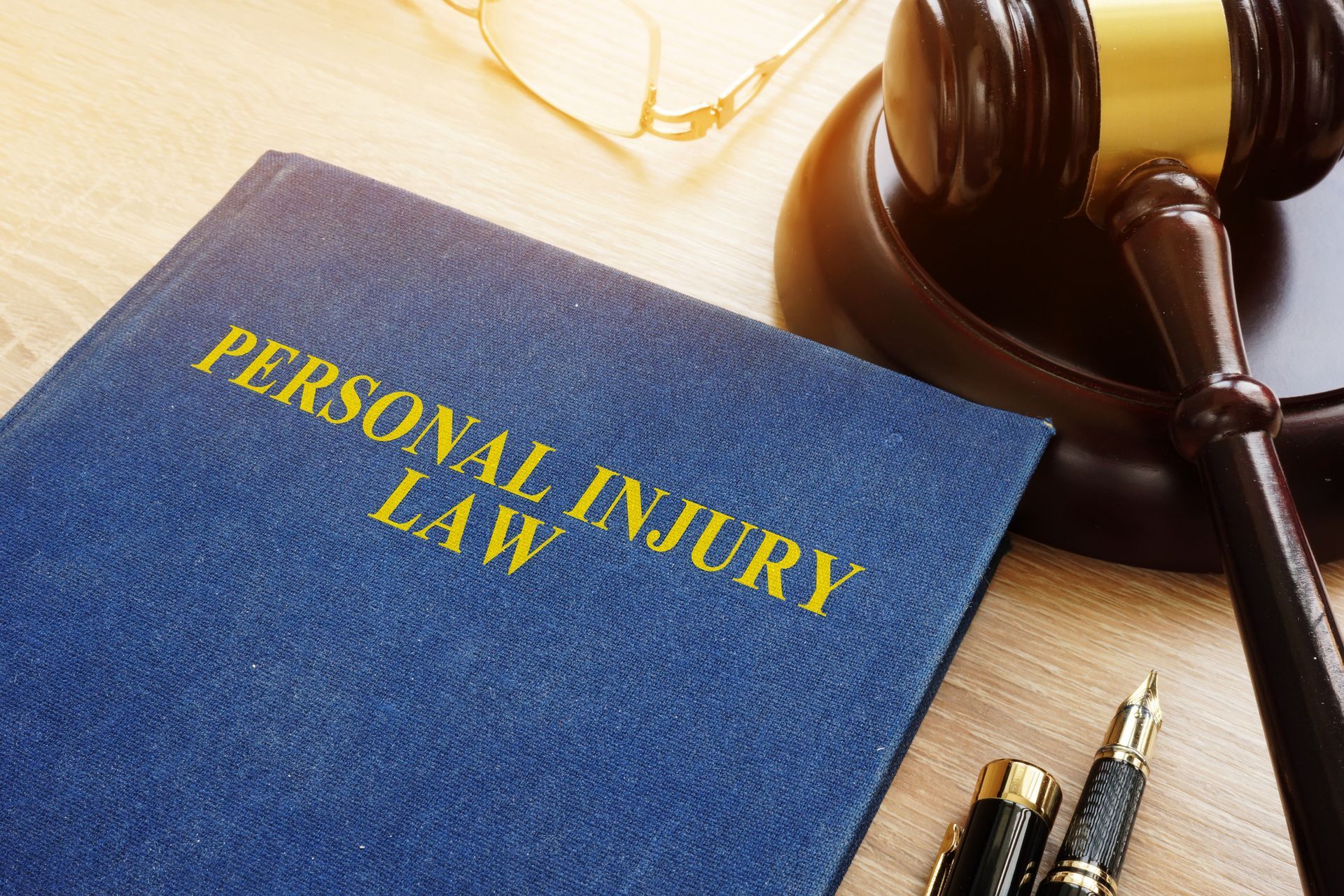 A personal injury law book is sitting on a wooden table next to a judge 's gavel.