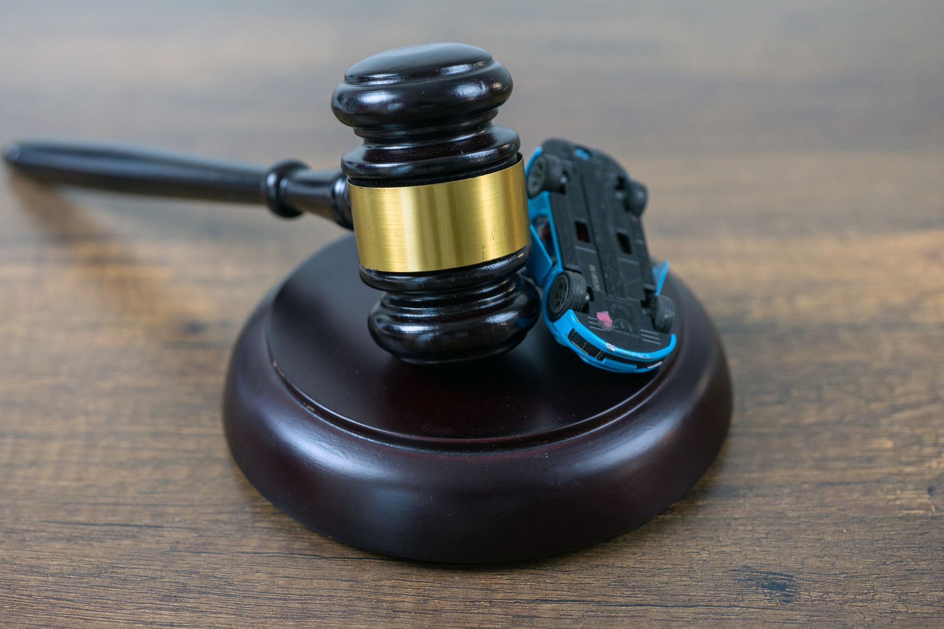 A judge 's gavel and a toy car on a wooden table.