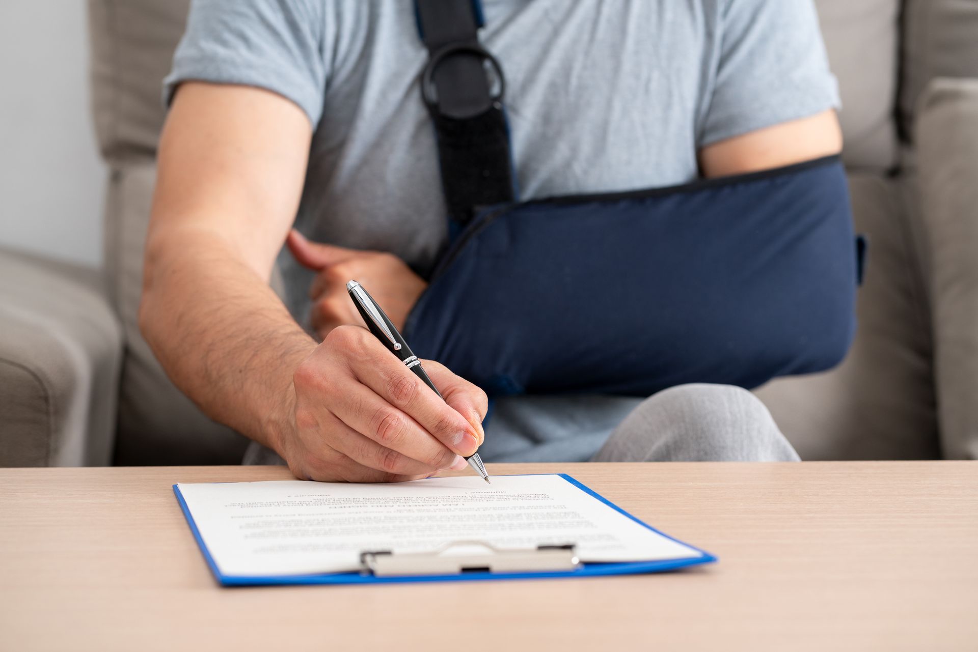 A man with a broken arm is writing on a clipboard.