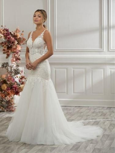 Woman in a white mermaid wedding dress with lace bodice, posing indoors.