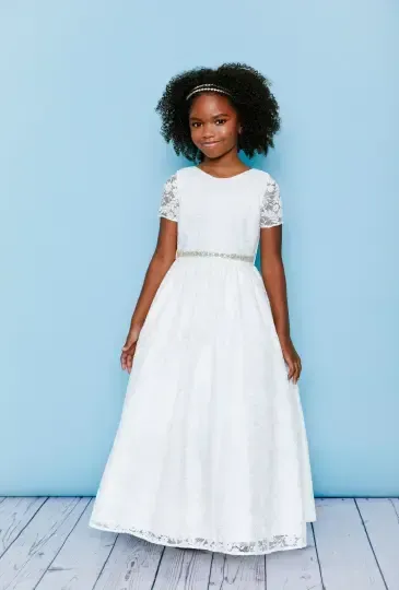 Girl in white formal dress smiles in front of a light blue backdrop.