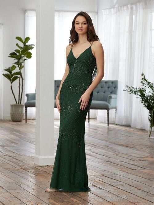 Woman in a green, sequined evening gown poses indoors.