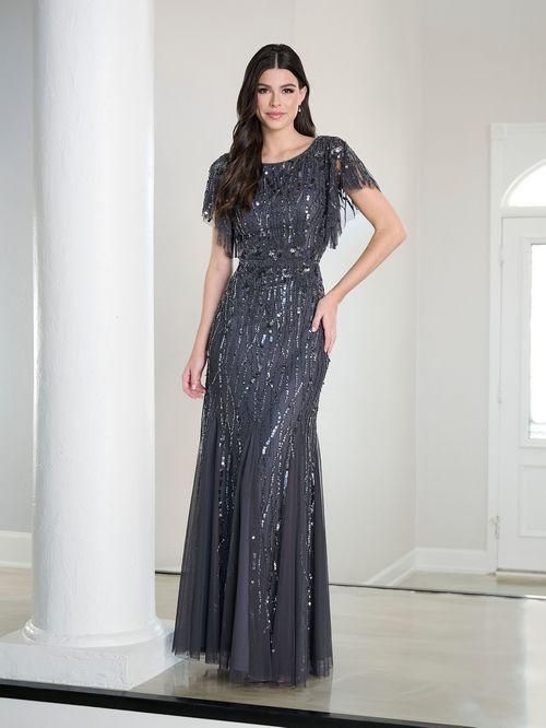 Woman in a sparkly gray formal gown, posing in front of a white pillar, hallway.