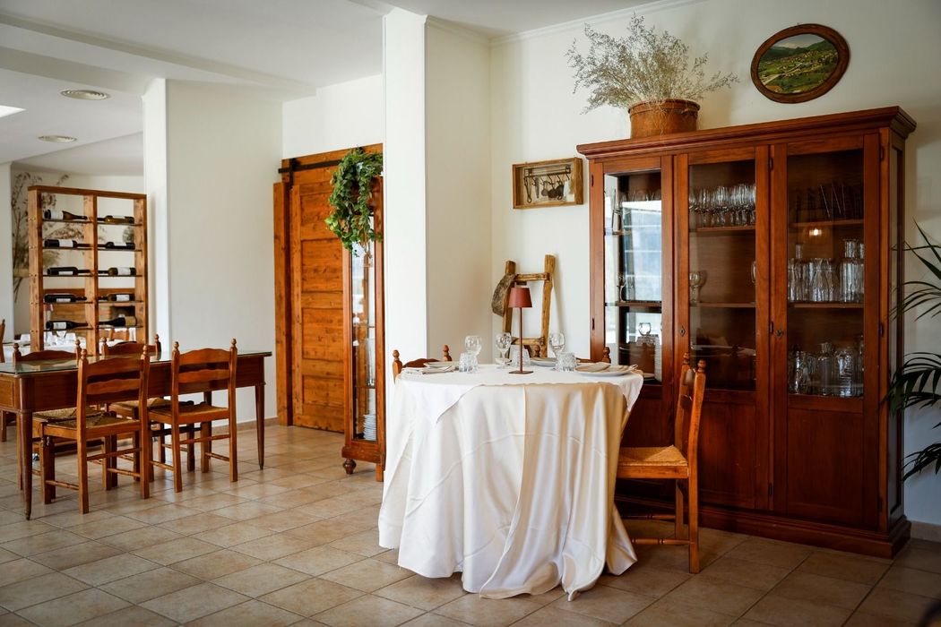 Terrazza ristorante all'aperto con tavoli, travi in ​​legno e una rigogliosa vista sulle montagne verdi.