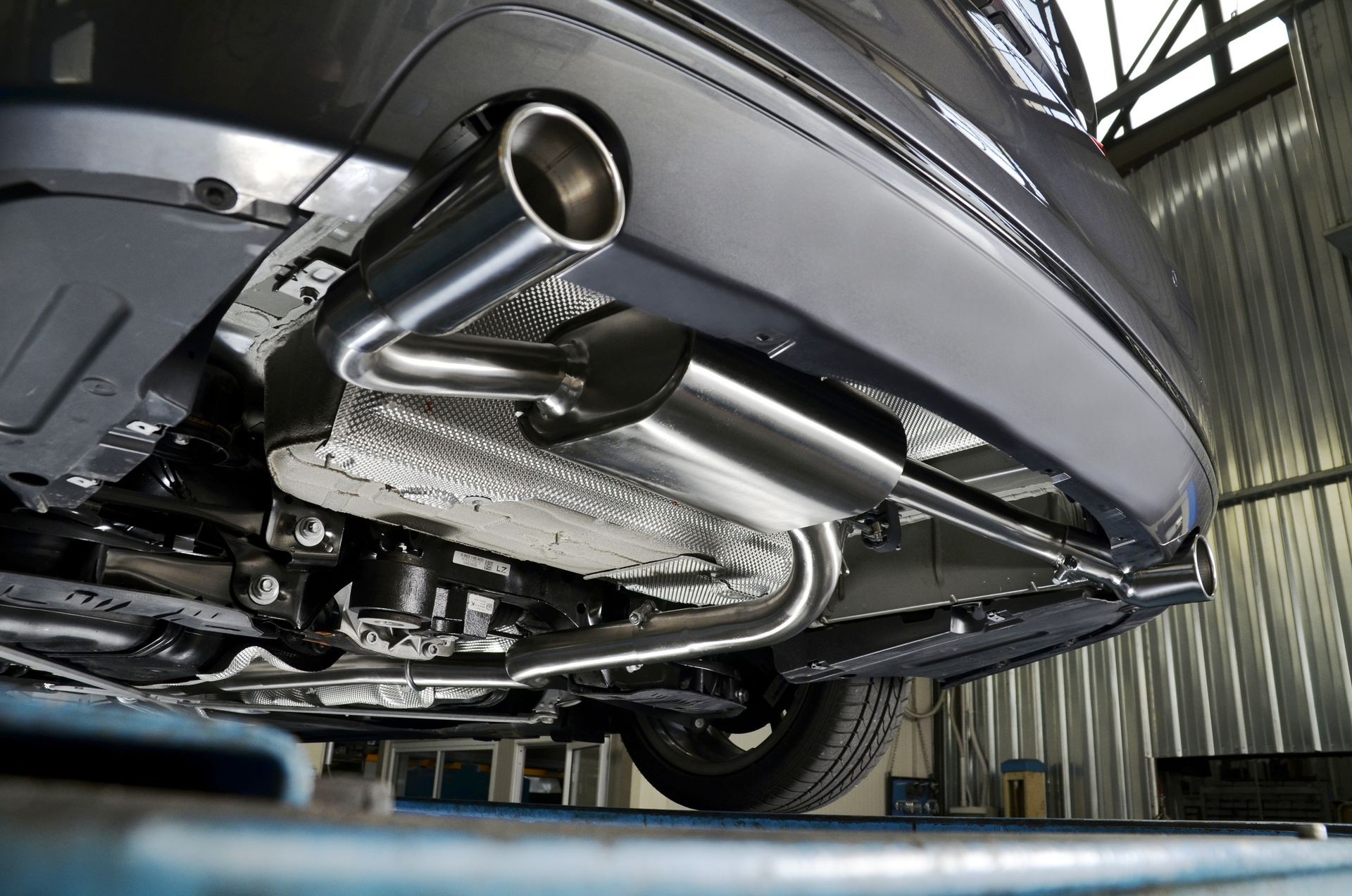 Underside view of a car showing the exhaust system with a chrome muffler and tailpipe.
