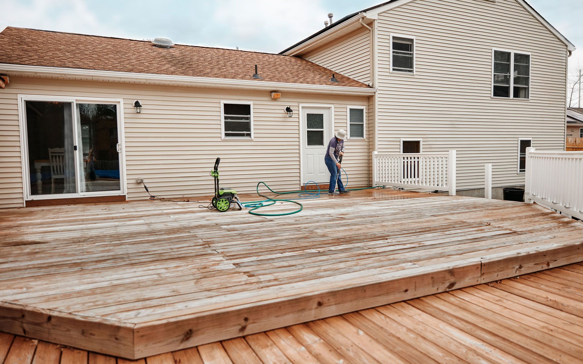 A man is standing on a wooden deck in front of a house.