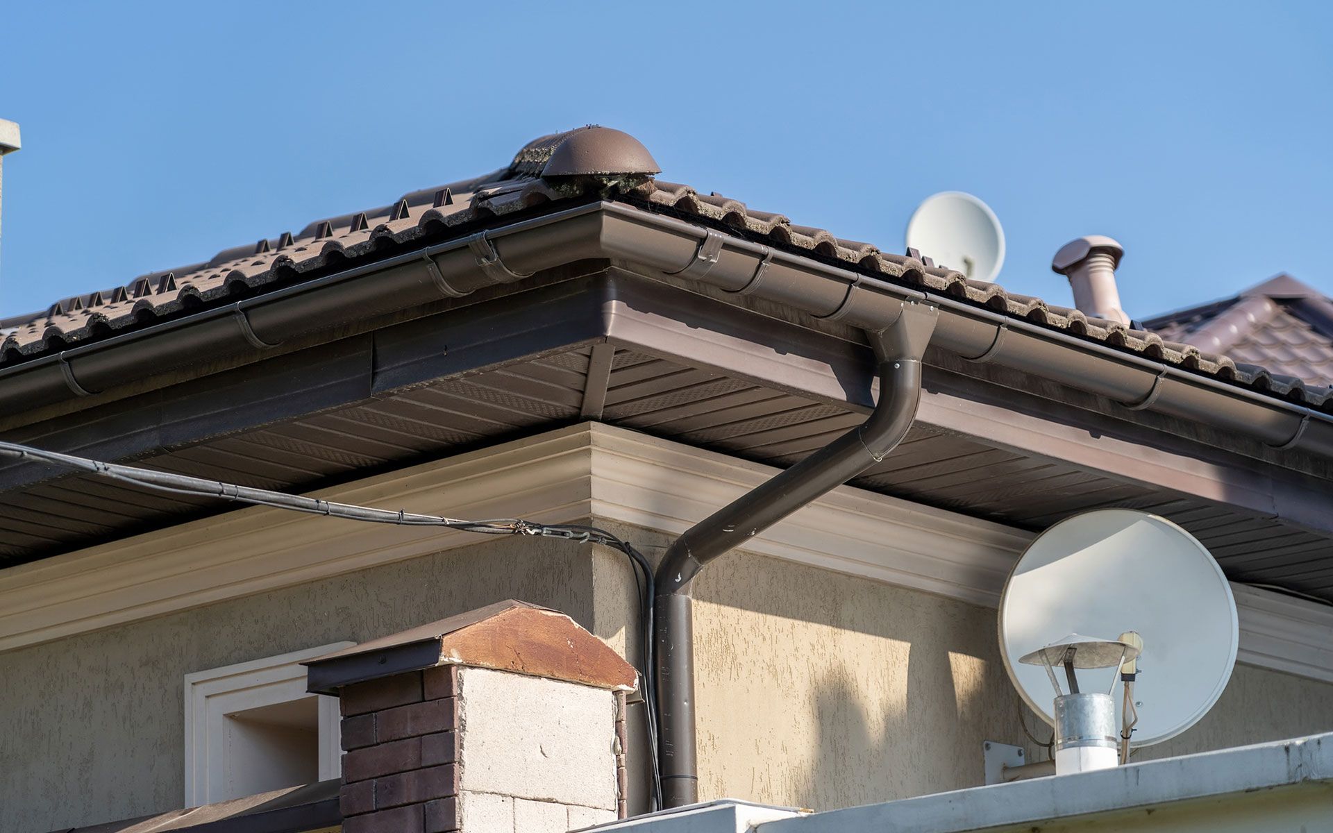 A house with a gutter and satellite dish on the roof.
