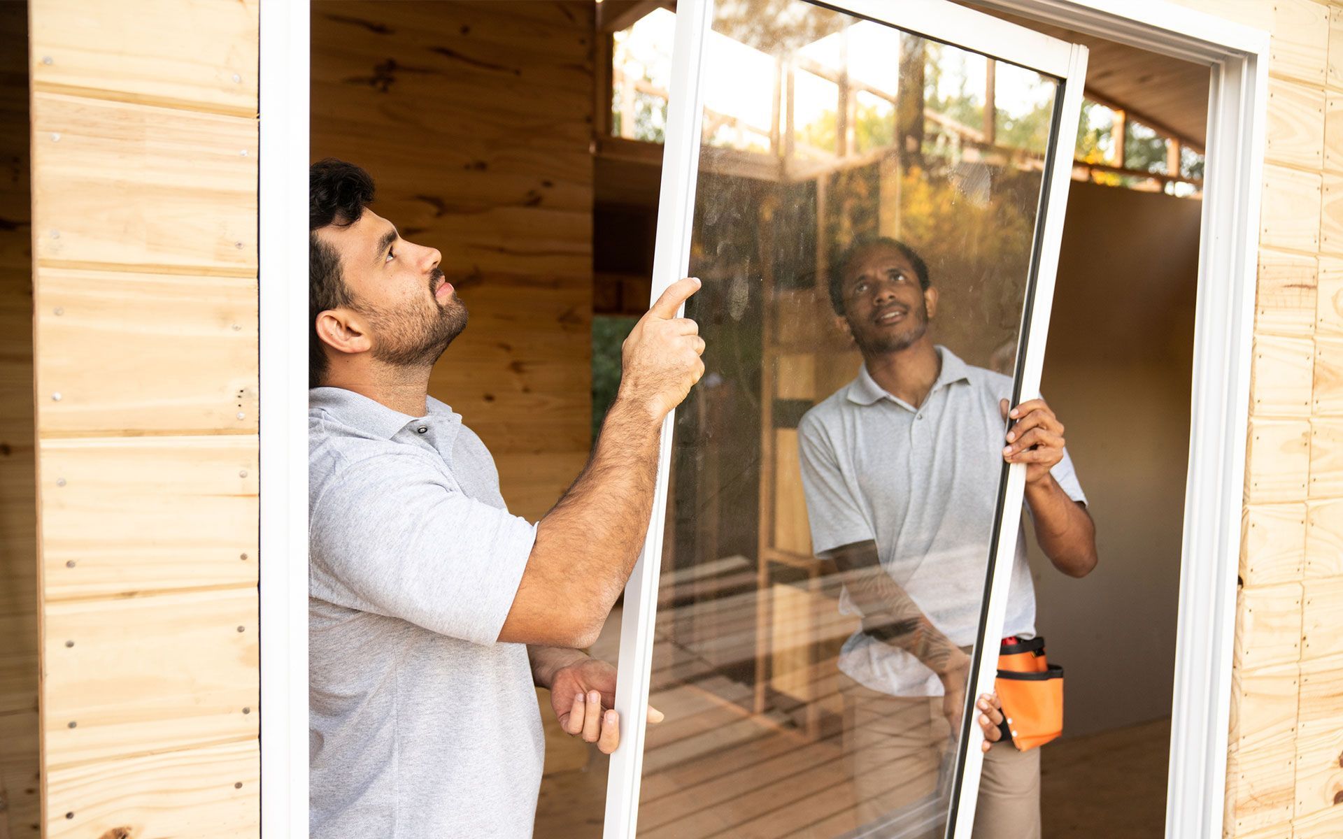 A man is installing a window in a wooden house.