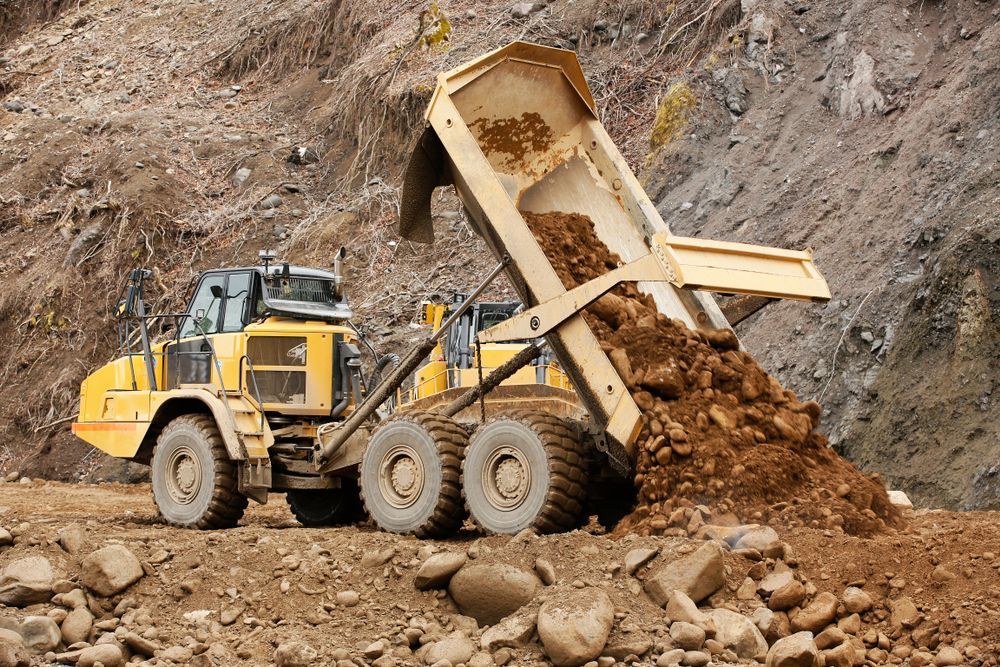 Yellow Dump Truck Unloading Soil at a Rocky Construction Site — Barkly Hire in Dugald River, QLD