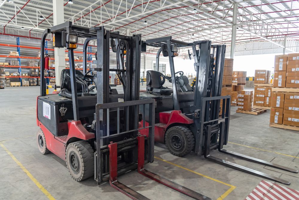 Two Red Forklifts Parked Inside a Warehouse Aisle With Stacked Boxes — Barkly Hire in Ryan, QLD